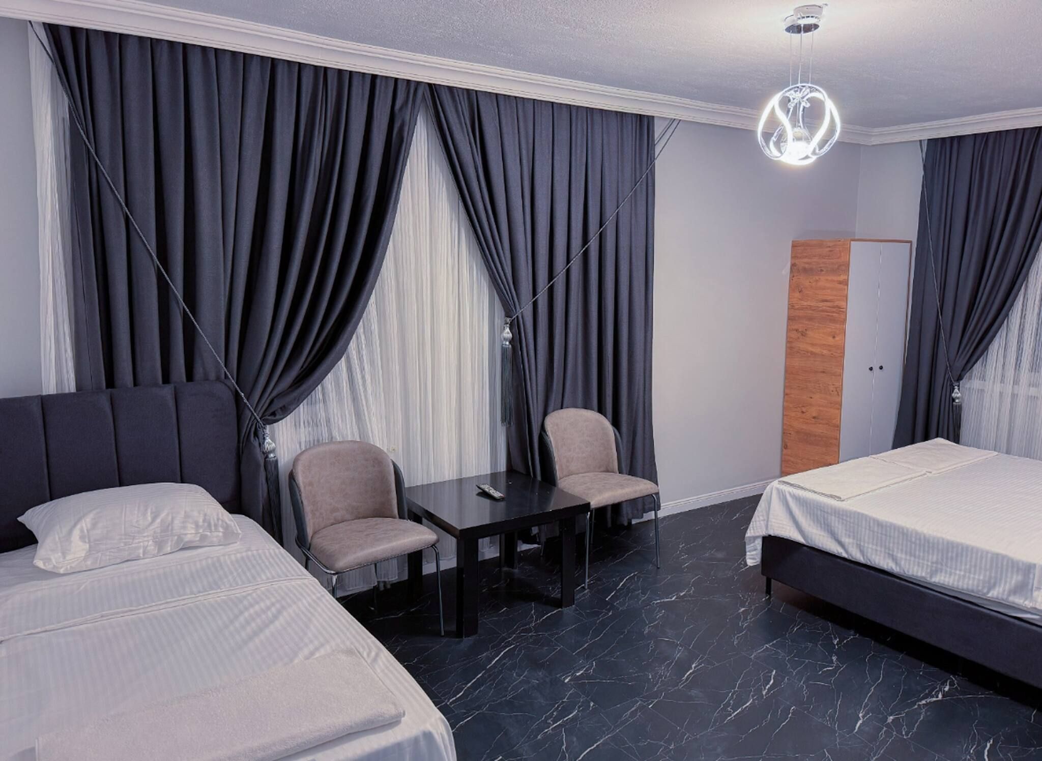 Une chambre d’hôtel avec deux lits, une petite table, une chaise et un bureau.