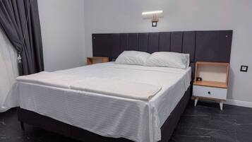 Une chambre moderne avec un grand lit, deux tables de chevet et une tête de lit dotée d’un éclairage intégré.