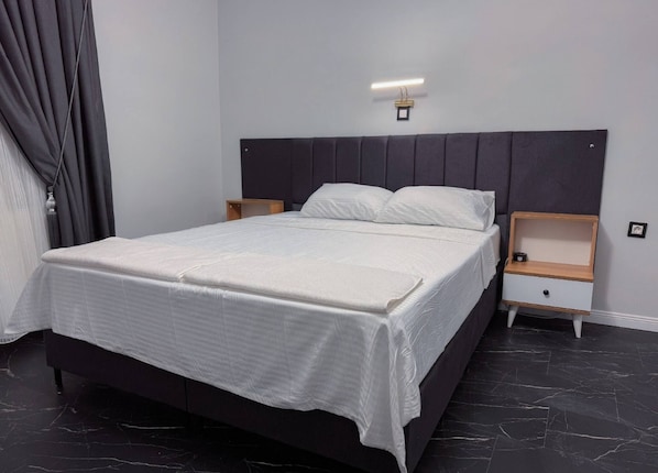 A modern bedroom with a large bed, two bedside tables, and a headboard with integrated lighting.