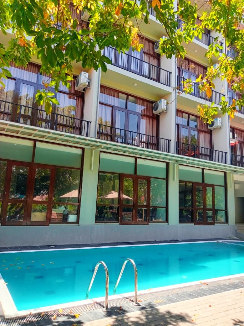 A hotel with a swimming pool, large windows, and balconies.