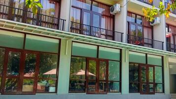 A hotel with a swimming pool, large windows, and balconies.