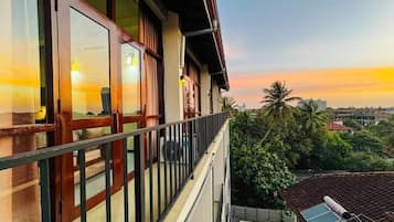 Ein Balkon mit Blick auf einen Sonnenuntergang, ein Gebäude mit großen Fenstern und eine Solarpanel auf dem Dach.