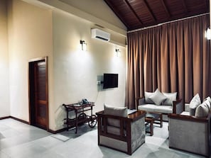A modern living room with a sofa, armchairs, a coffee table, and a TV mounted on the wall. - Leisureo hotel & spa (Negombo)