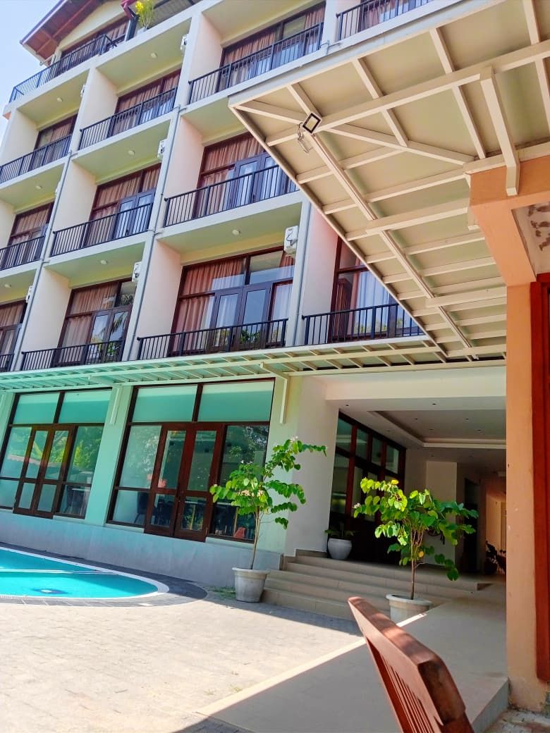 A multi-story hotel with balconies, a swimming pool, and a covered entrance.