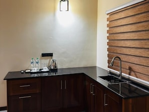 Una cocina con encimera negra, un fregadero y paneles de madera en la pared.