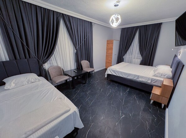 A hotel room with two beds, a desk, and a chair.