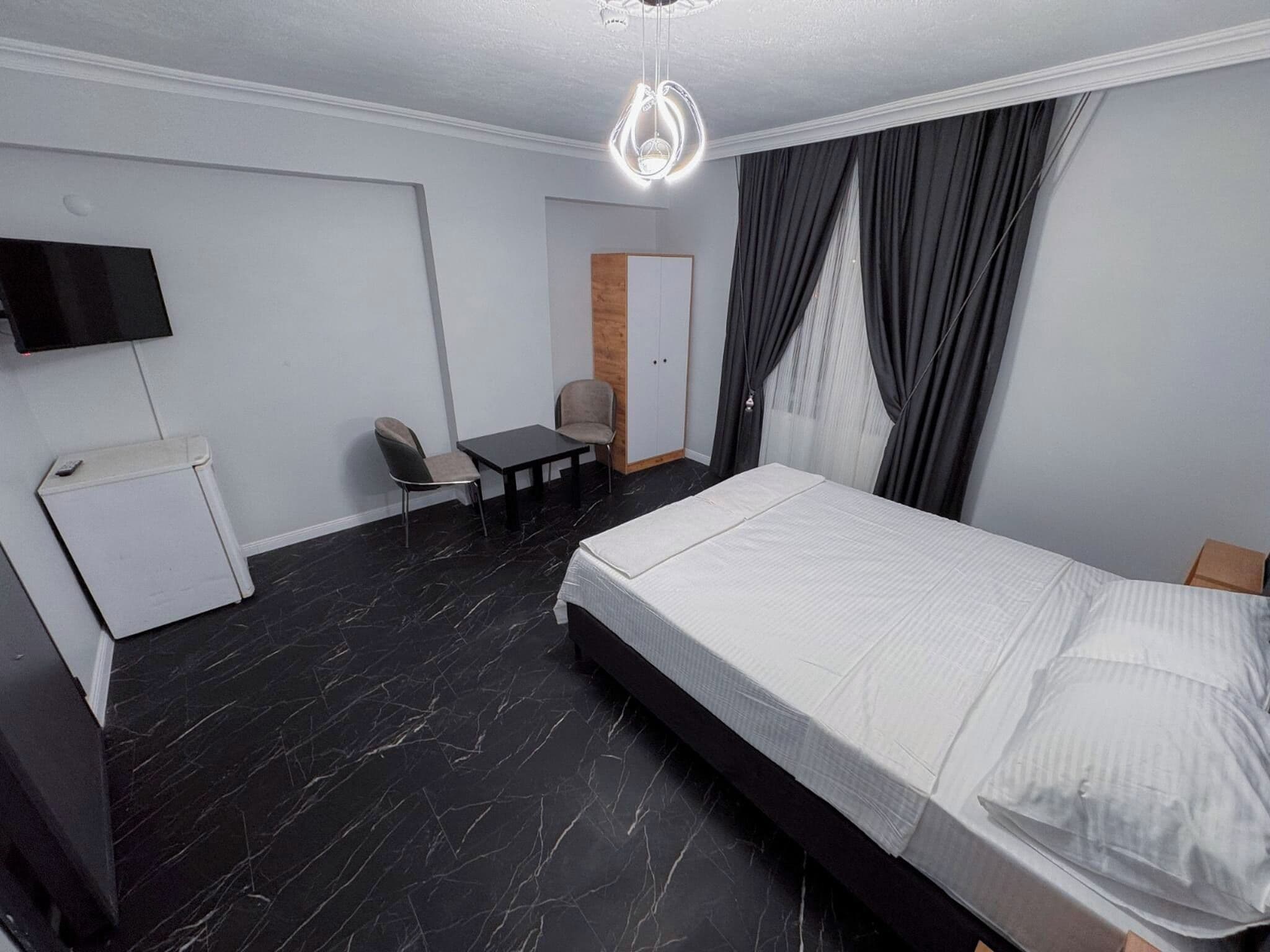Une chambre d’hôtel comprenant un lit, un bureau, une chaise, une armoire et un téléviseur.