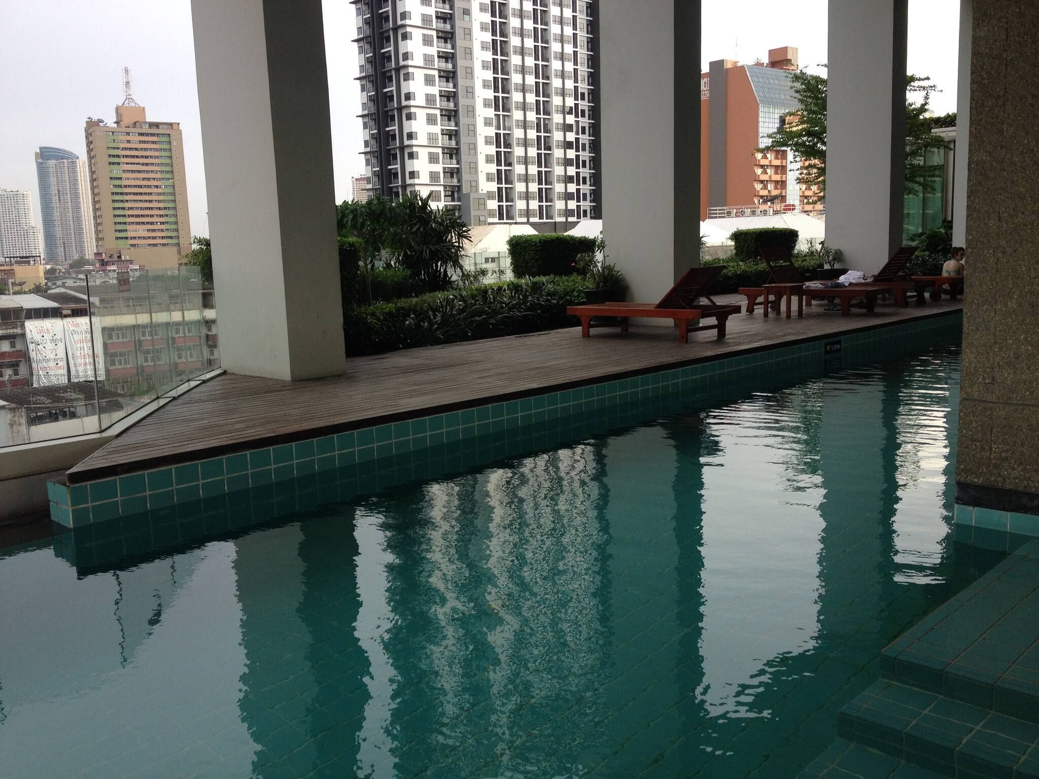 A swimming pool with lounge chairs and a city view.
