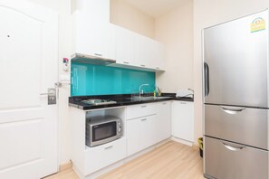 A compact kitchen with a built-in oven, a stainless steel refrigerator, and a teal backsplash. - Luxurious 2-Bedroom Apartment Near Chao Phraya River (Bangkok)