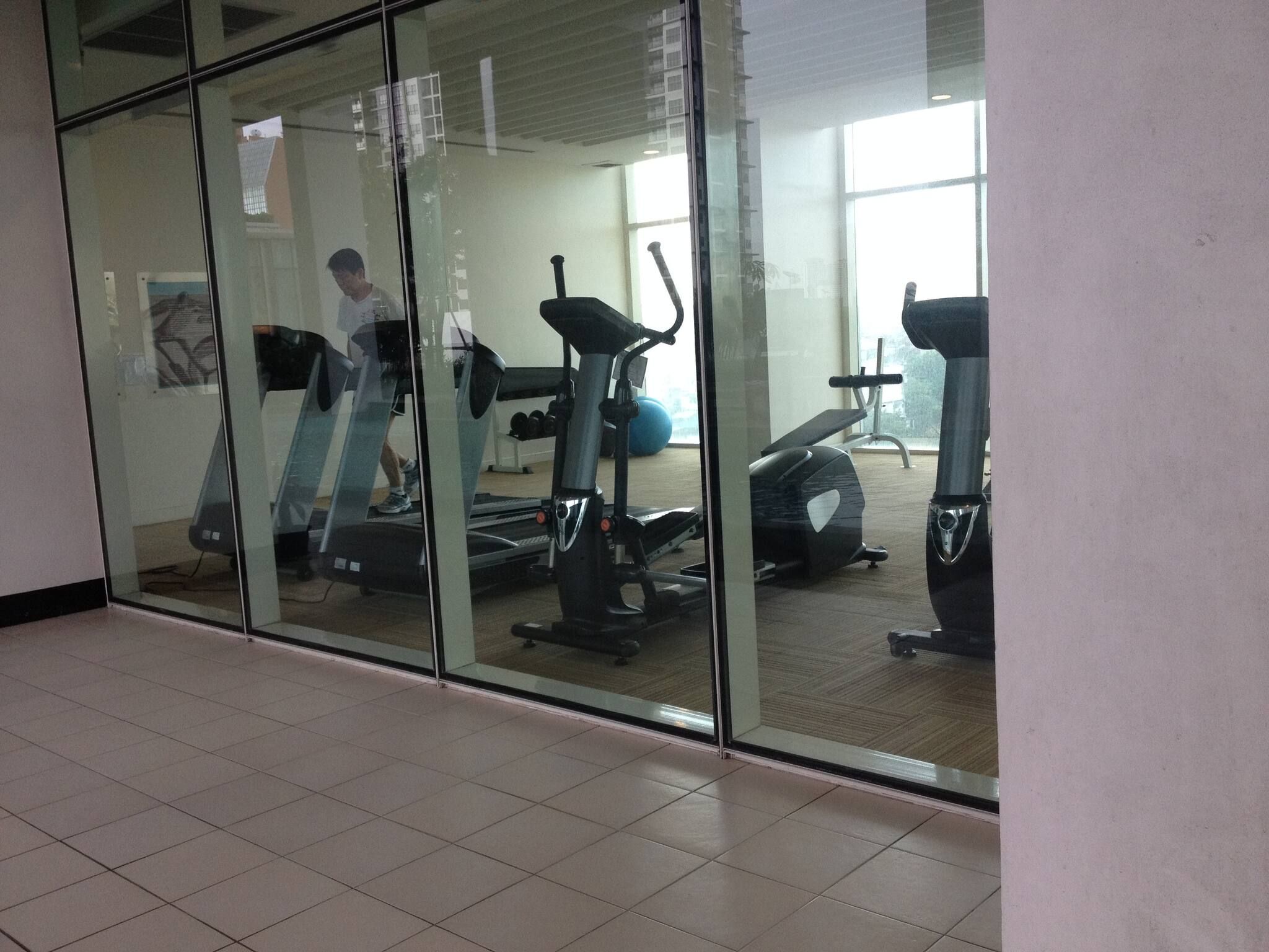 A gym with exercise equipment, including treadmills and a stationary bike, and a person walking on a treadmill.