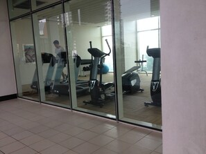 A gym with exercise equipment, including treadmills and a stationary bike, and a person walking on a treadmill. - Luxurious 2-Bedroom Apartment Near Chao Phraya River (Bangkok)