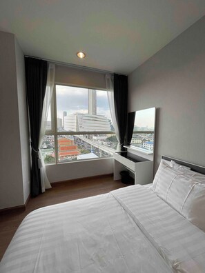 Ein Hotelzimmer mit einem großen Bett, einem Schreibtisch und Blick auf eine Stadtansicht.