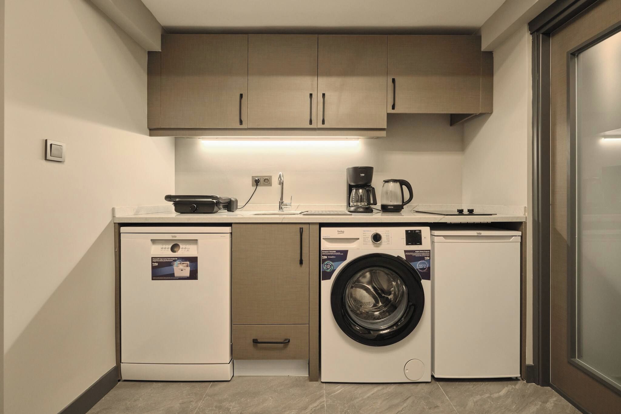 A compact kitchen with a washing machine, a coffee maker, and a dishwasher.