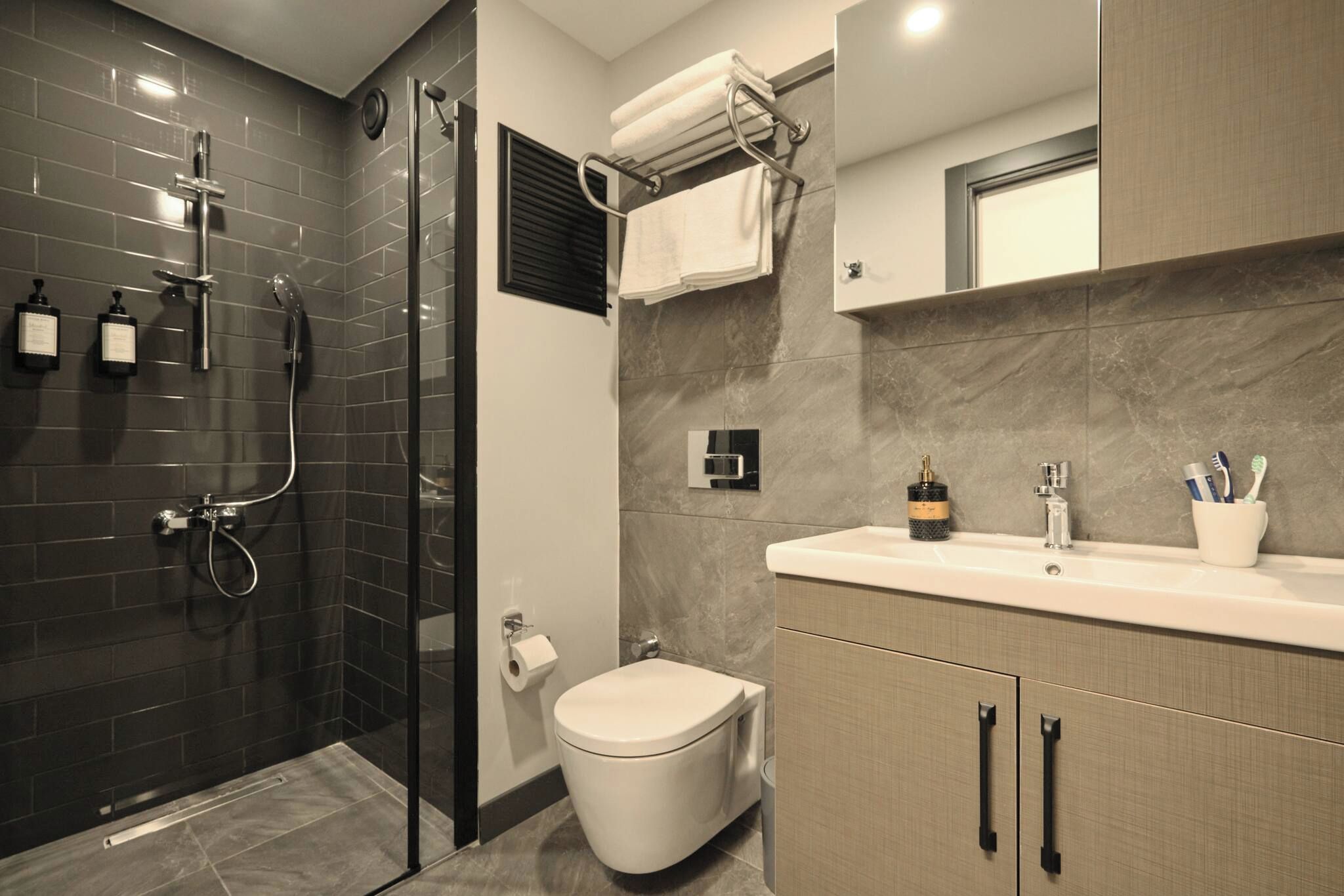 A modern bathroom with a glass-enclosed shower, a toilet, and a vanity with a mirror and sink.