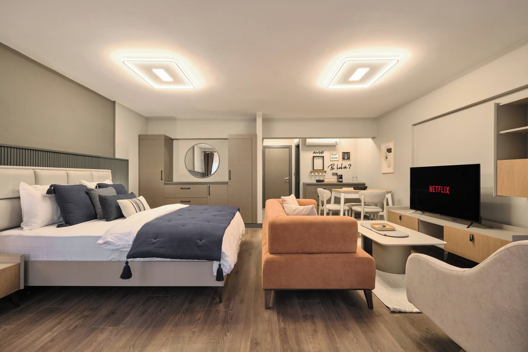 A modern hotel room with a bed, a sofa, a desk, and a television.