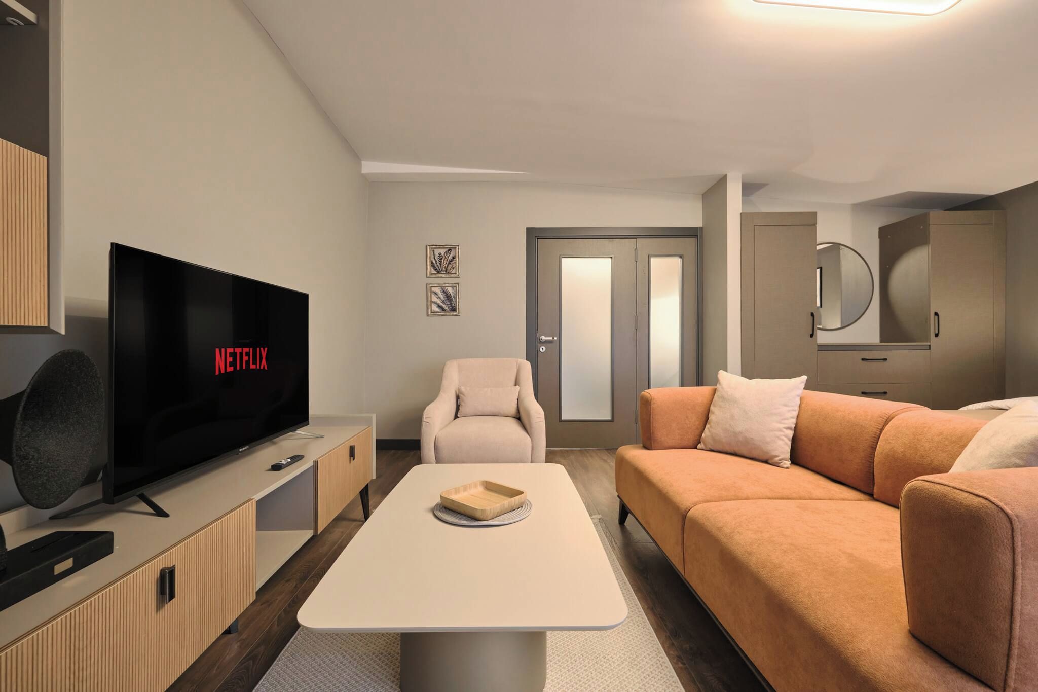 A modern living room with a flat-screen TV, a sofa, a chair, and a coffee table.