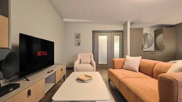 A modern living room with a flat-screen TV, a sofa, a chair, and a coffee table.