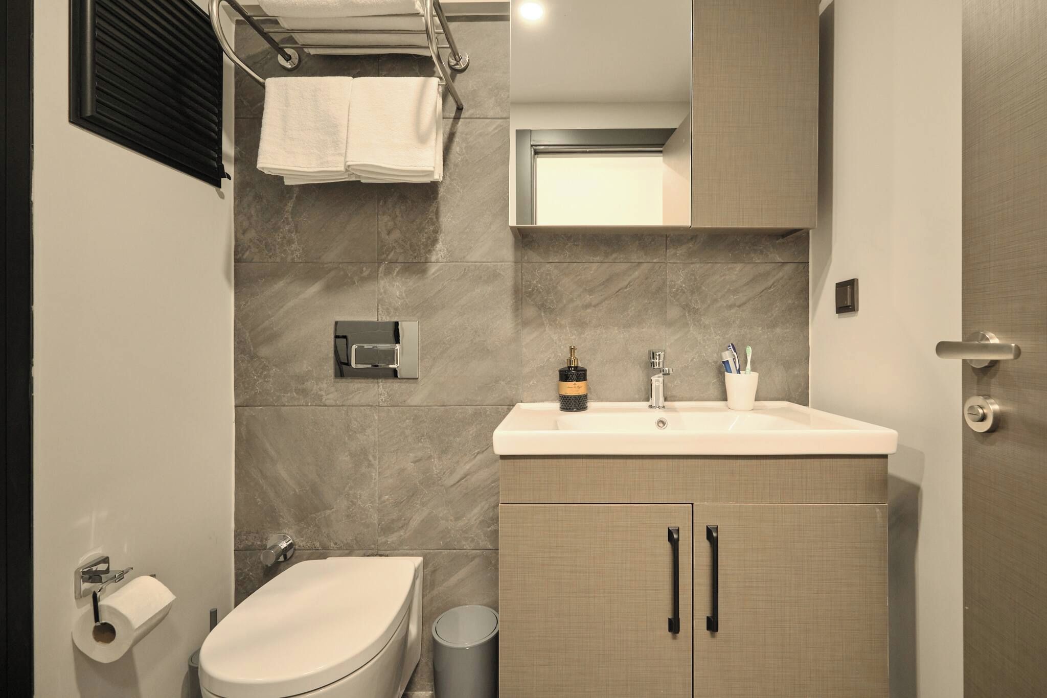 A modern bathroom with a toilet, sink, and mirror.