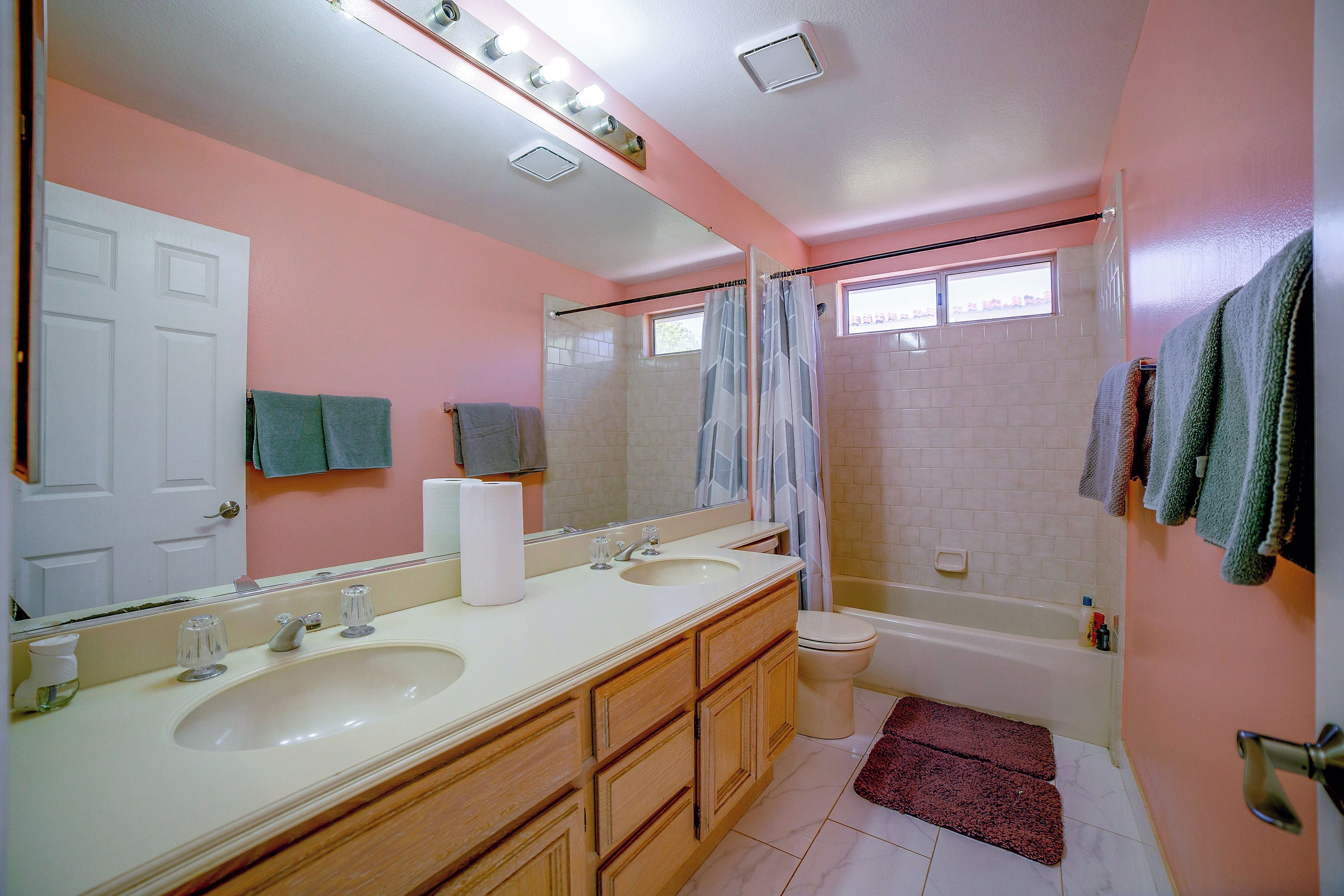 A bathroom with two sinks, a toilet, a bathtub, and a shower curtain.