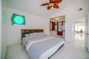 A bedroom with a bed, a ceiling fan, a wardrobe, and a bathroom visible through an open door.