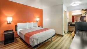 A hotel room with a bed, a desk, and a kitchenette. - 1 Queen Bed | Micfridge (Youngtown)