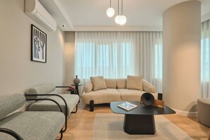 A modern living room with a sofa, chairs, a coffee table, and a large window with curtains. - Nakamura, 3BR, Serene, Charming (Kadıköy)