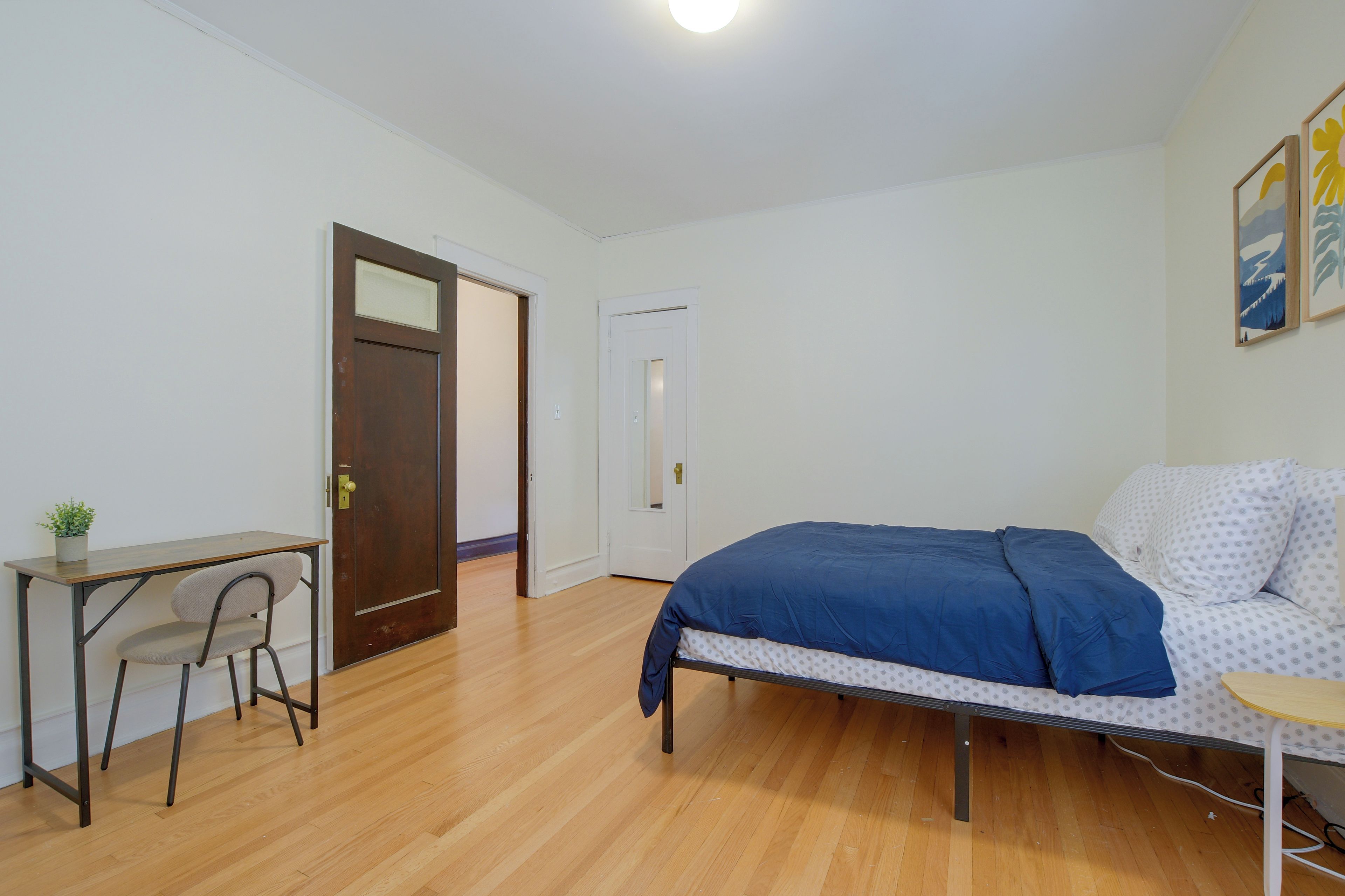 A bedroom with a bed, a desk, and a chair.