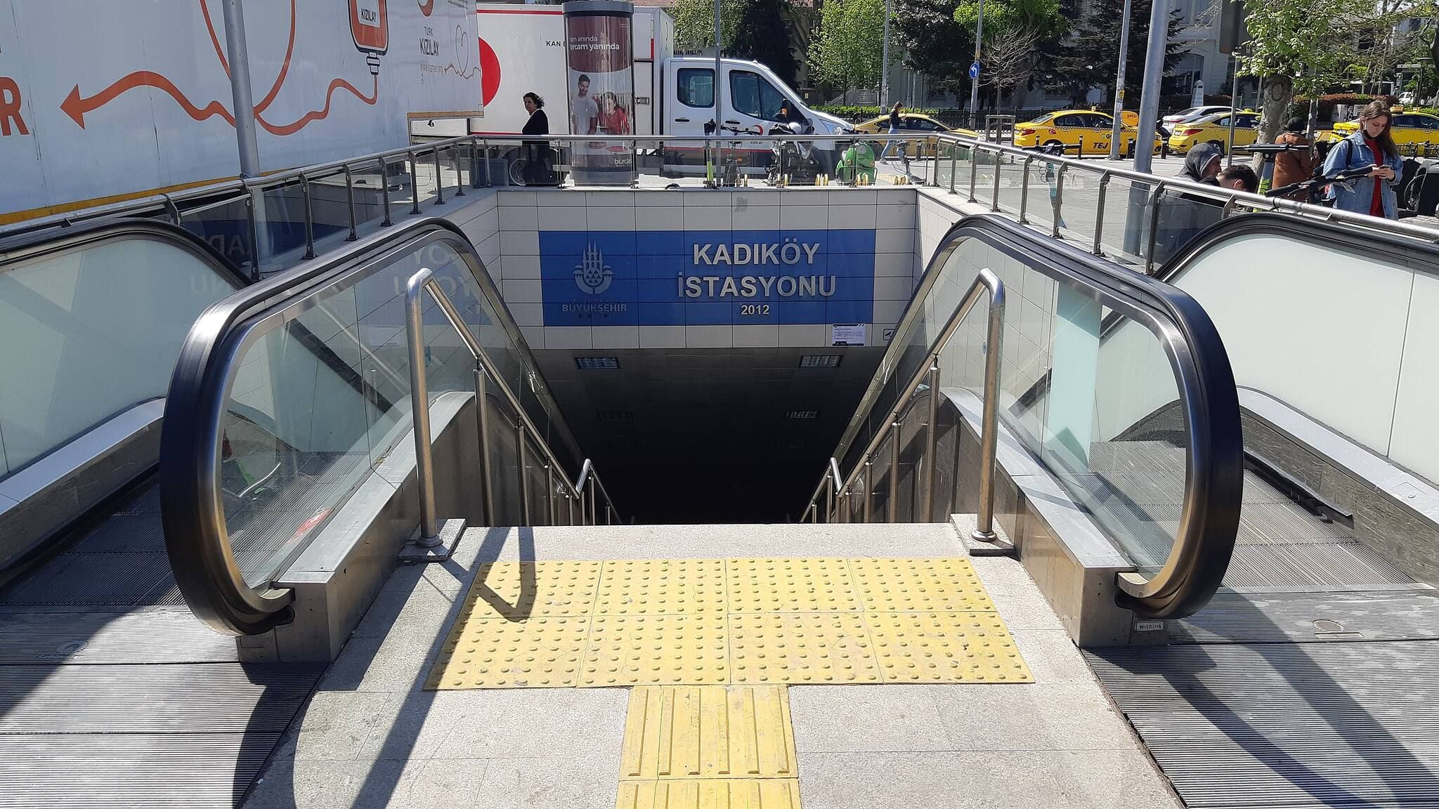 Una escala interior que condueix a una estació de metro amb un senyal que diu 'KADIKOY ISTASYONU'.