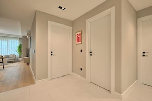 A hallway with two white doors, a framed picture on the wall, and a plant in the corner. - Caruana, 2BR, Peaceful, Modern (Kadıköy)
