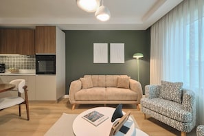 A modern living space with a kitchen, a sofa, a patterned armchair, and a dining area. - Caruana, 2BR, Peaceful, Modern (Kadıköy)