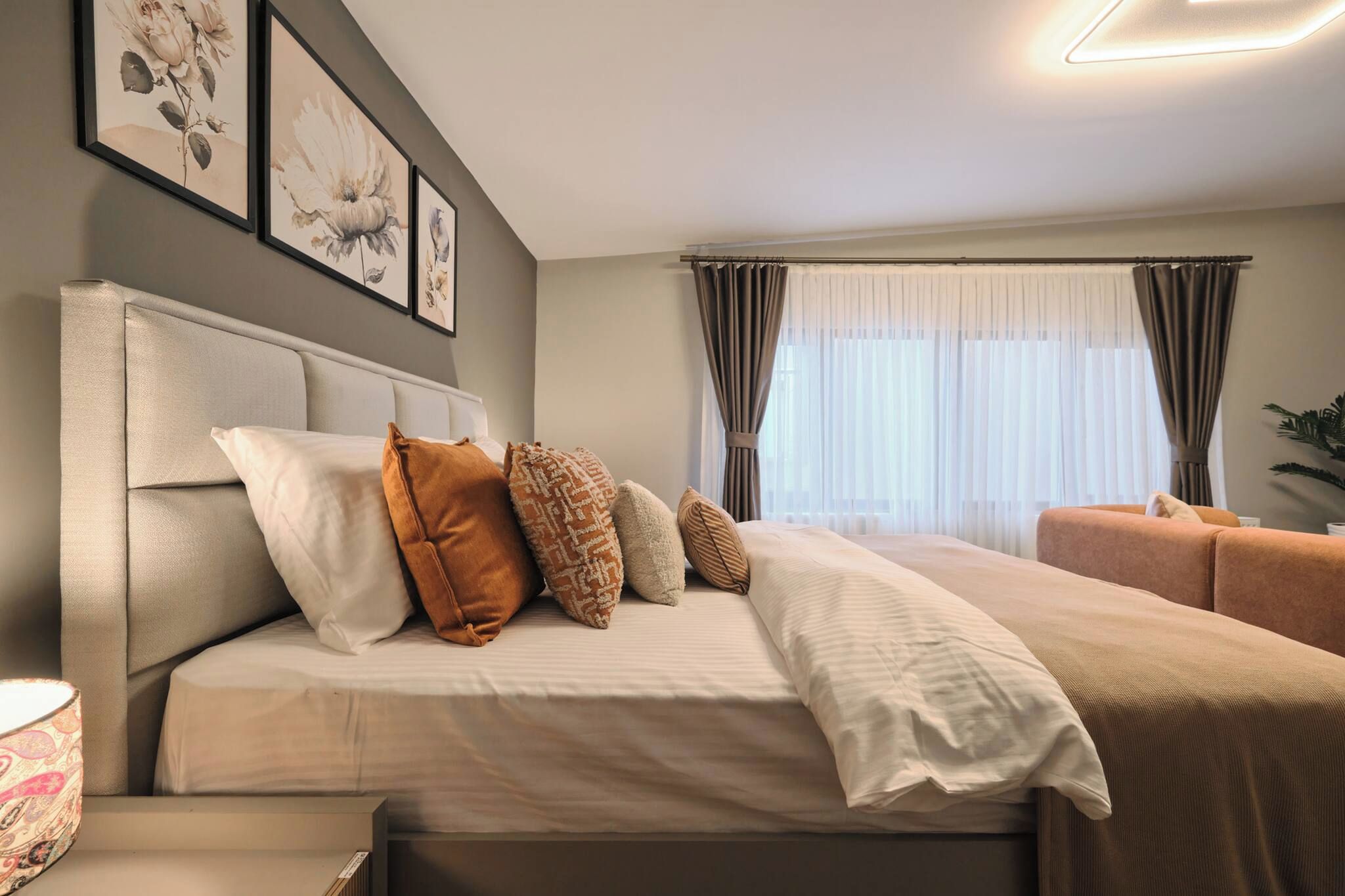 A bedroom with a bed, pillows, a bedside table, and a window with curtains.