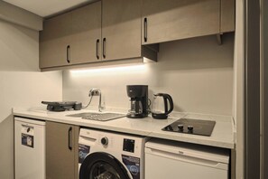 A compact kitchenette with a washing machine, a coffee maker, and a small sink. - Modern 2BR Living Areas, 2 Baths, Kadıköy (Kadıköy)