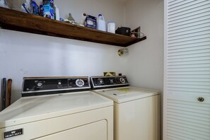 A laundry room with two White Westinghouse heavy-duty washers, a wooden shelf above containing cleaning supplies, and a white door with a window. - Long-Range Views in Gated Wolf Laurel/Ski/Ashville (Mars Hill)