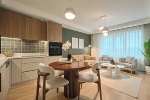 Eine moderne Küche mit Holzschränken, einem eingebauten Ofen und einem Essbereich mit einem runden Tisch und Stühlen.