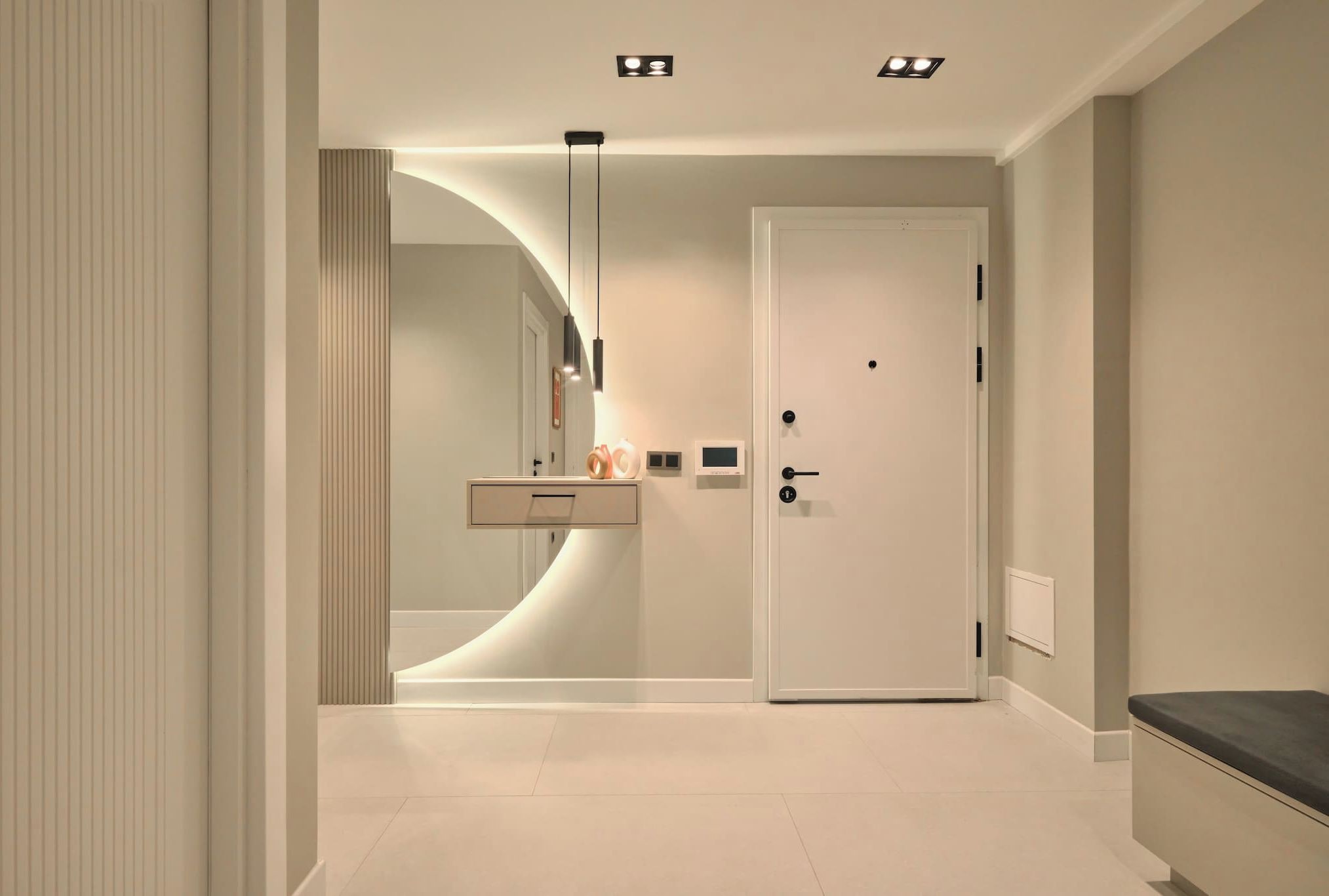 A modern bathroom with a curved vanity, a toilet, and a shower area.