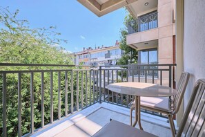 A balcony with a table and chairs, overlooking a residential area with trees and buildings. - Orion, Fancy 2BR, Best Loc (Kadıköy)