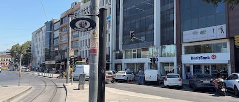 Une vue de rue avec une ligne de tramway, une banque et divers commerces.