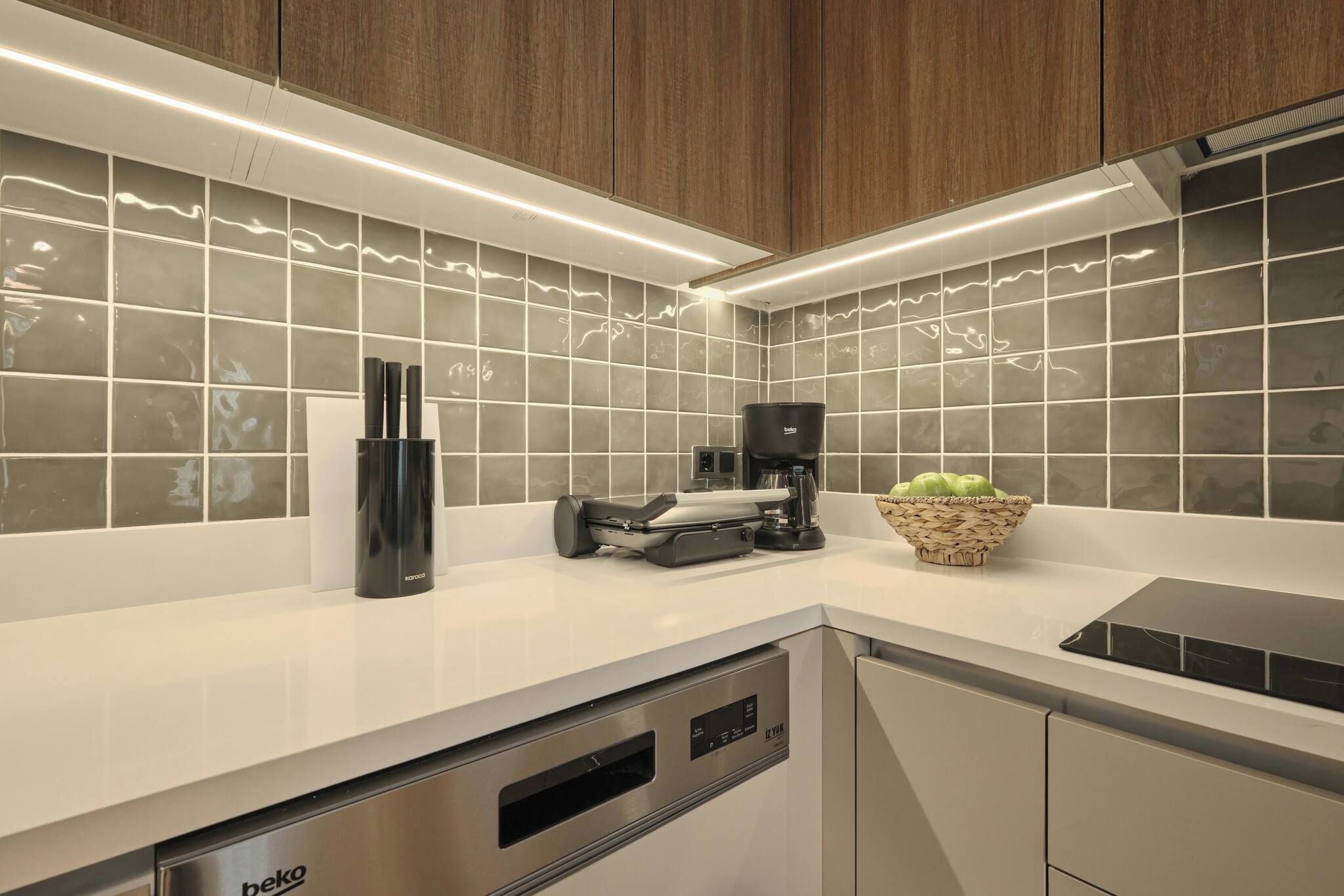 A modern kitchen with a built-in dishwasher, a coffee maker, and a fruit bowl on the counter.