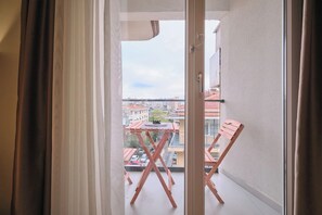A balcony with a table and chairs, a view of buildings, and a door. - Fischer, 2BR, Bright, Stylish (Kadıköy)