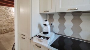 Una kitchenette con cafetera, un cajón con utensilios y un salpicadero con diseño.
