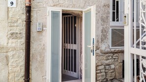 Un edificio de piedra con una puerta que da a un interior oscuro, un cartel con el número 9 y una ventana con una reja de metal.