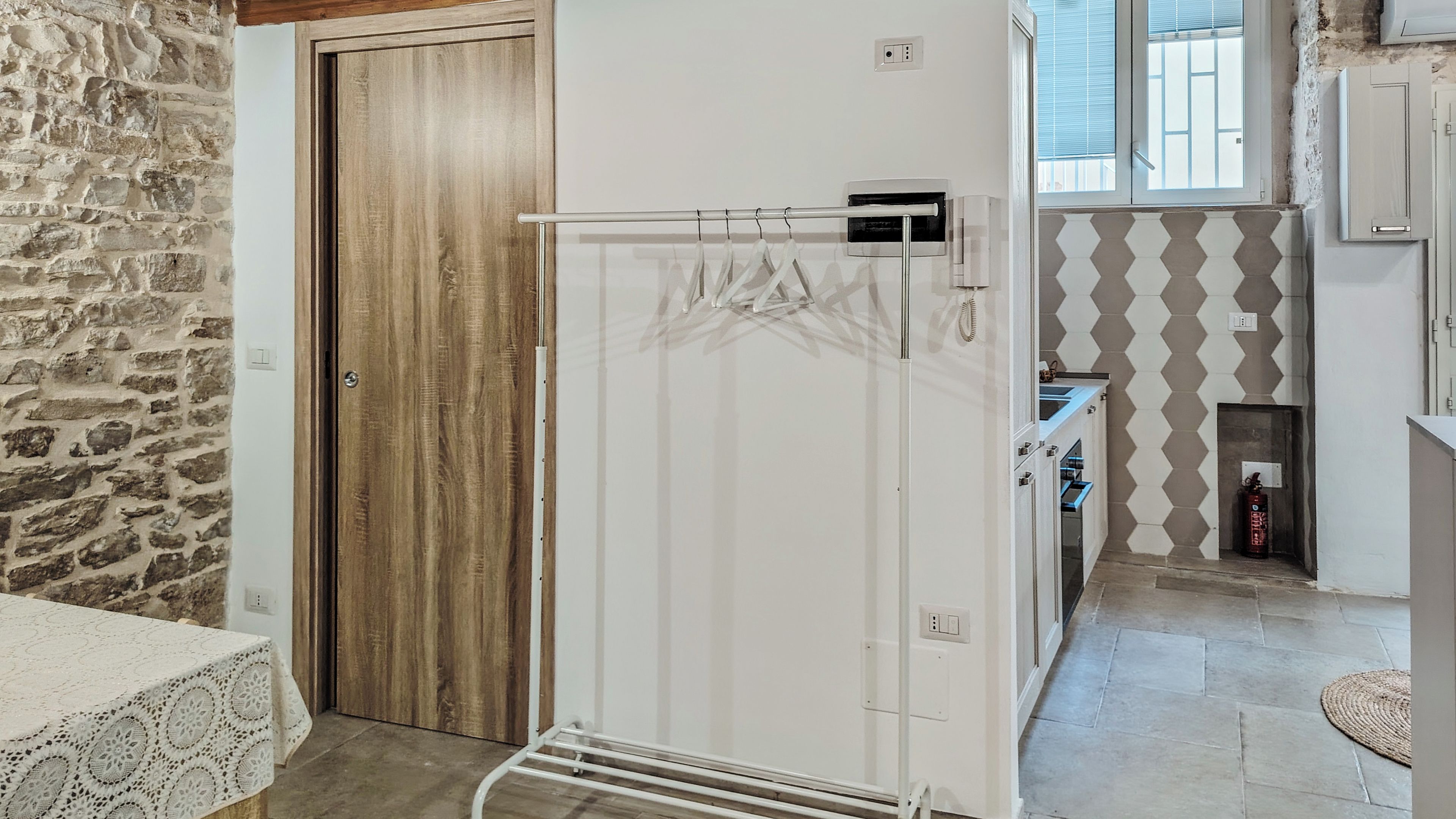 Een keuken met een witte koelkast, een houten deur, een stenen muur en een betegelde spatwand.