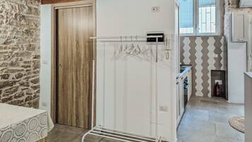 Een keuken met een witte koelkast, een houten deur, een stenen muur en een betegelde spatwand.