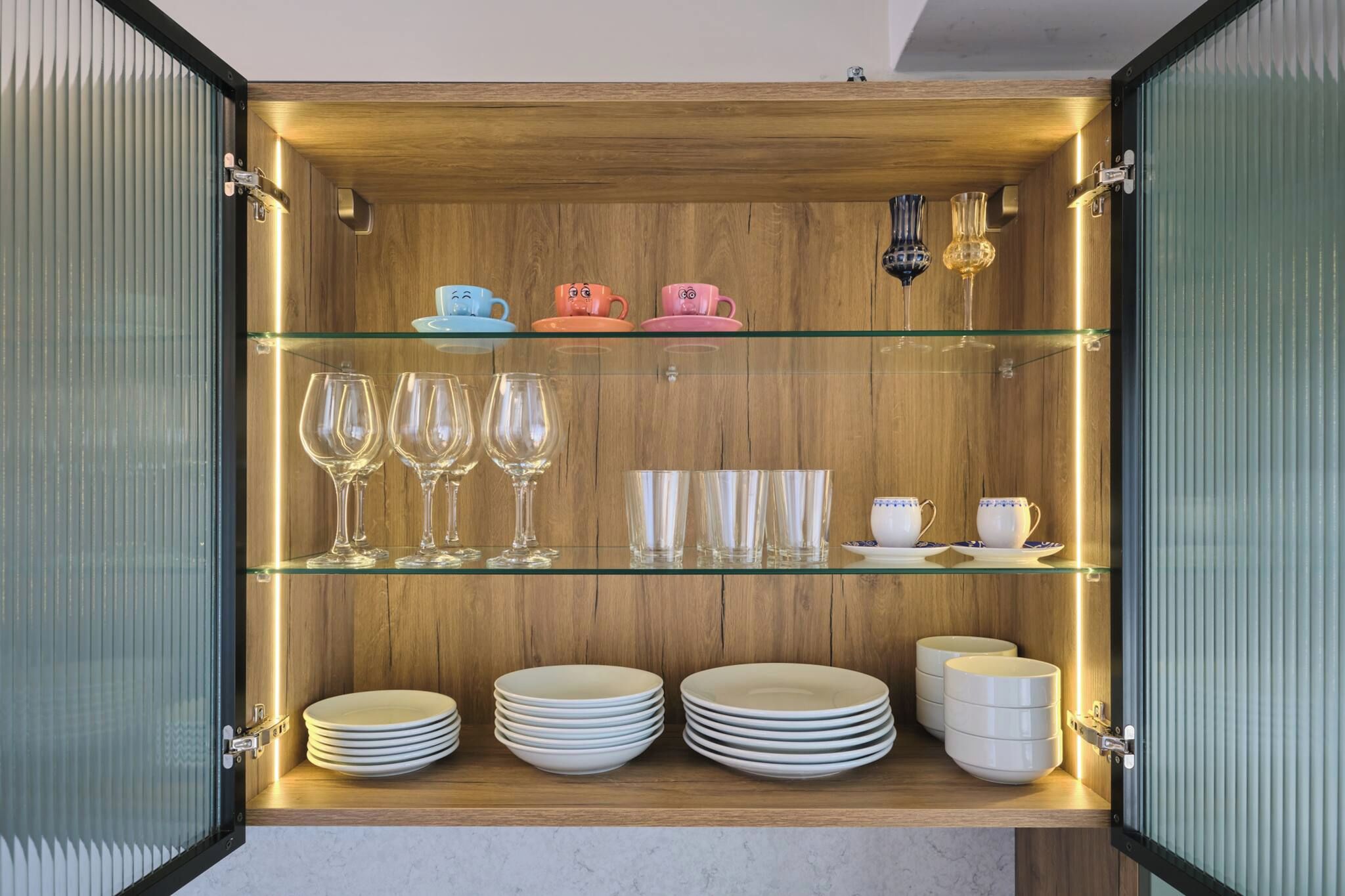 A storage unit with shelves containing plates, glasses, and cups.