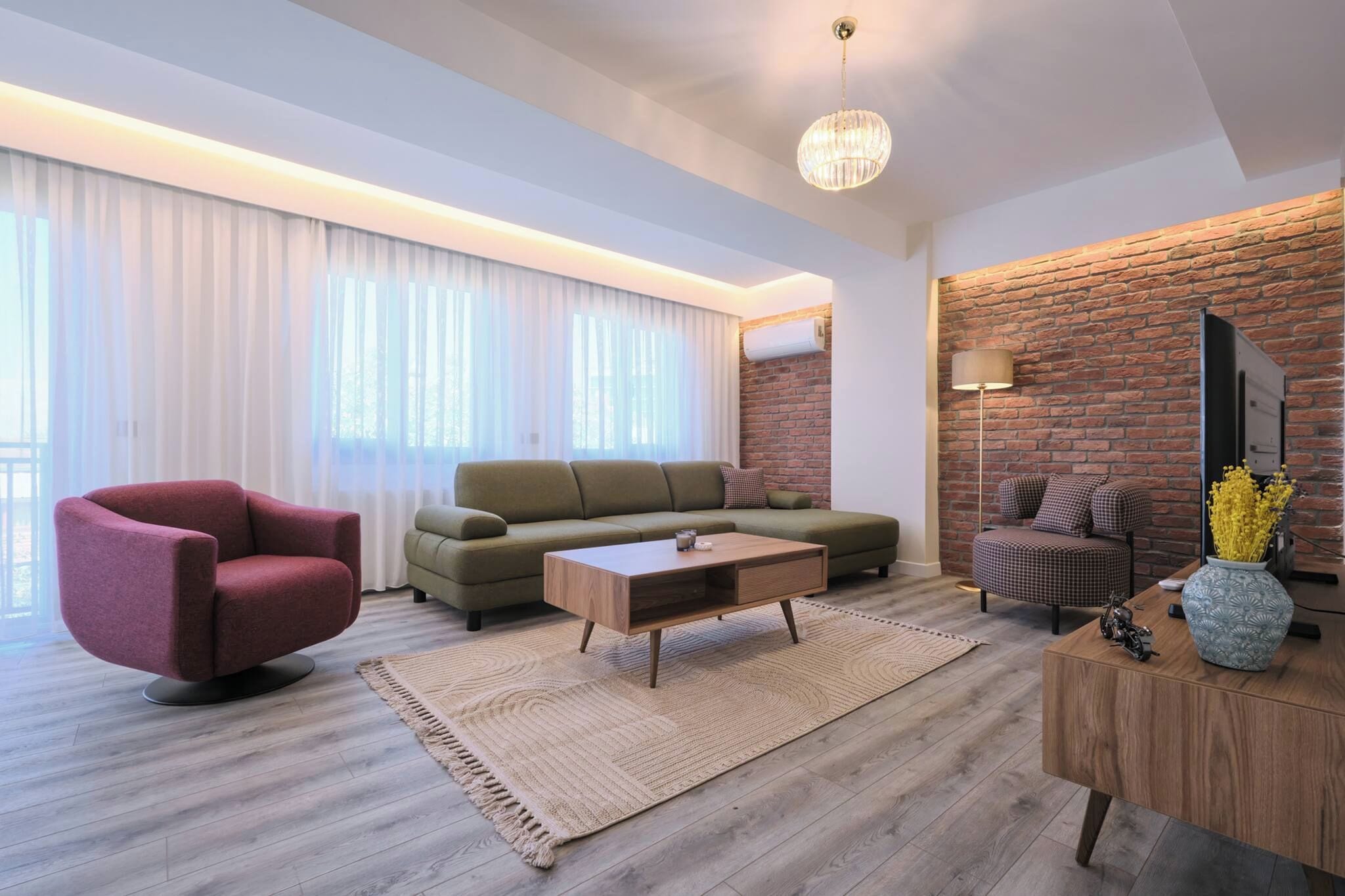 A modern living room with a sofa, armchair, coffee table, and a brick accent wall.