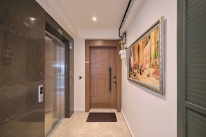 A hallway with a wooden door, a digital elevator control panel, and a framed painting on the wall. - Sirius, Modern 2BR, Best Loc (Kadıköy)