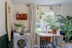 A laundry room with a washing machine, drying rack, and a table with potted plants. - Shop, Dine, Explore Dtwn! Walkable Farmington Home (Farmington)