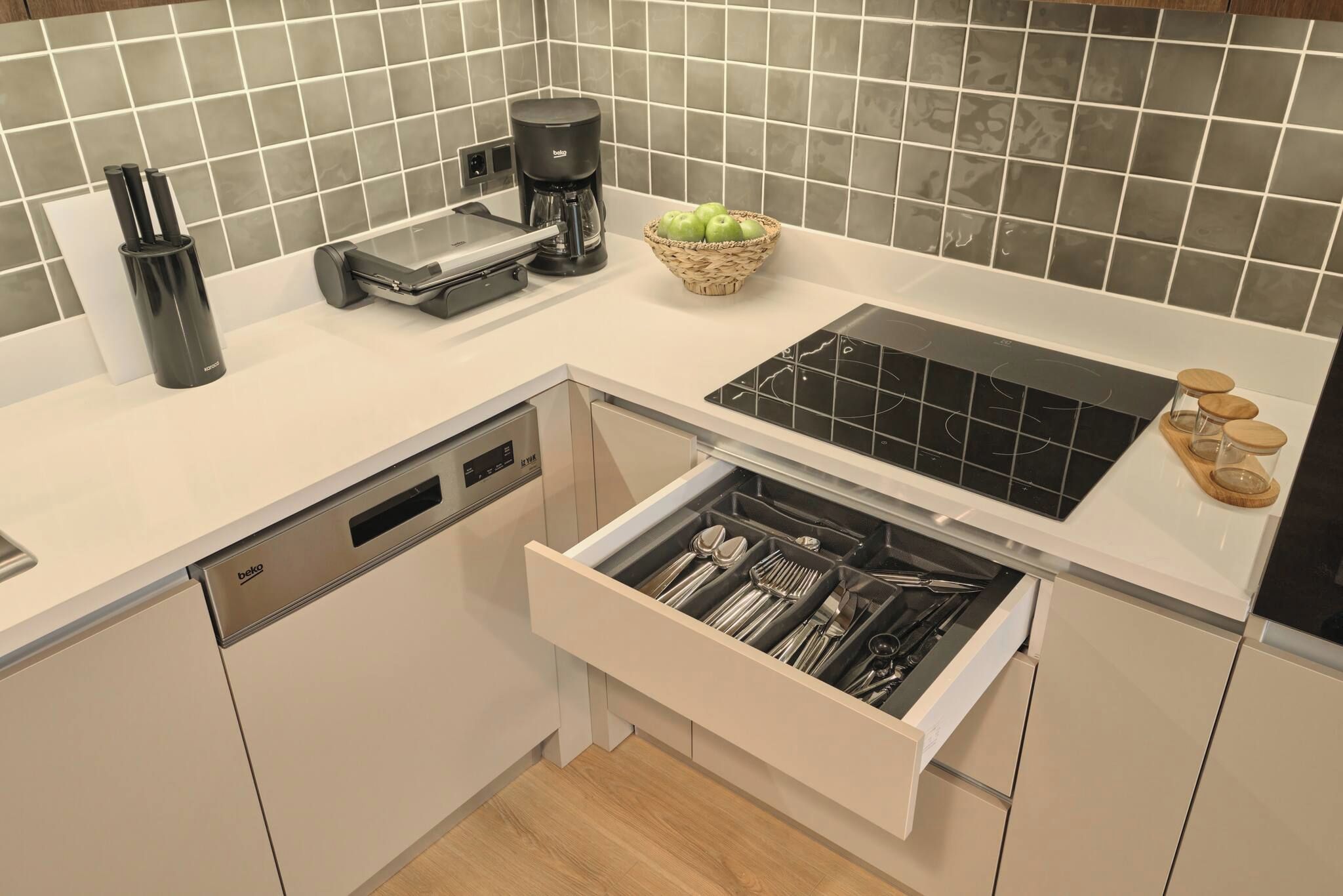 Een moderne keuken met een vaatwasser, koffiezetapparaat en een lade met bestek.