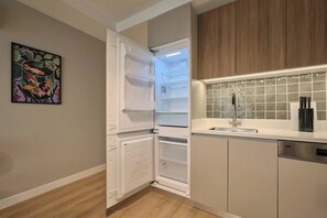 A modern kitchen with a built-in refrigerator, a sink, and a tiled backsplash. - Kramnik, 2BR, Cozy, Charming (Kadıköy)