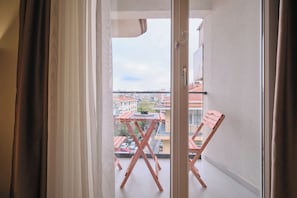 A balcony with a table and chairs, a view of buildings, and a door. - Kramnik, 2BR, Cozy, Charming (Kadıköy)